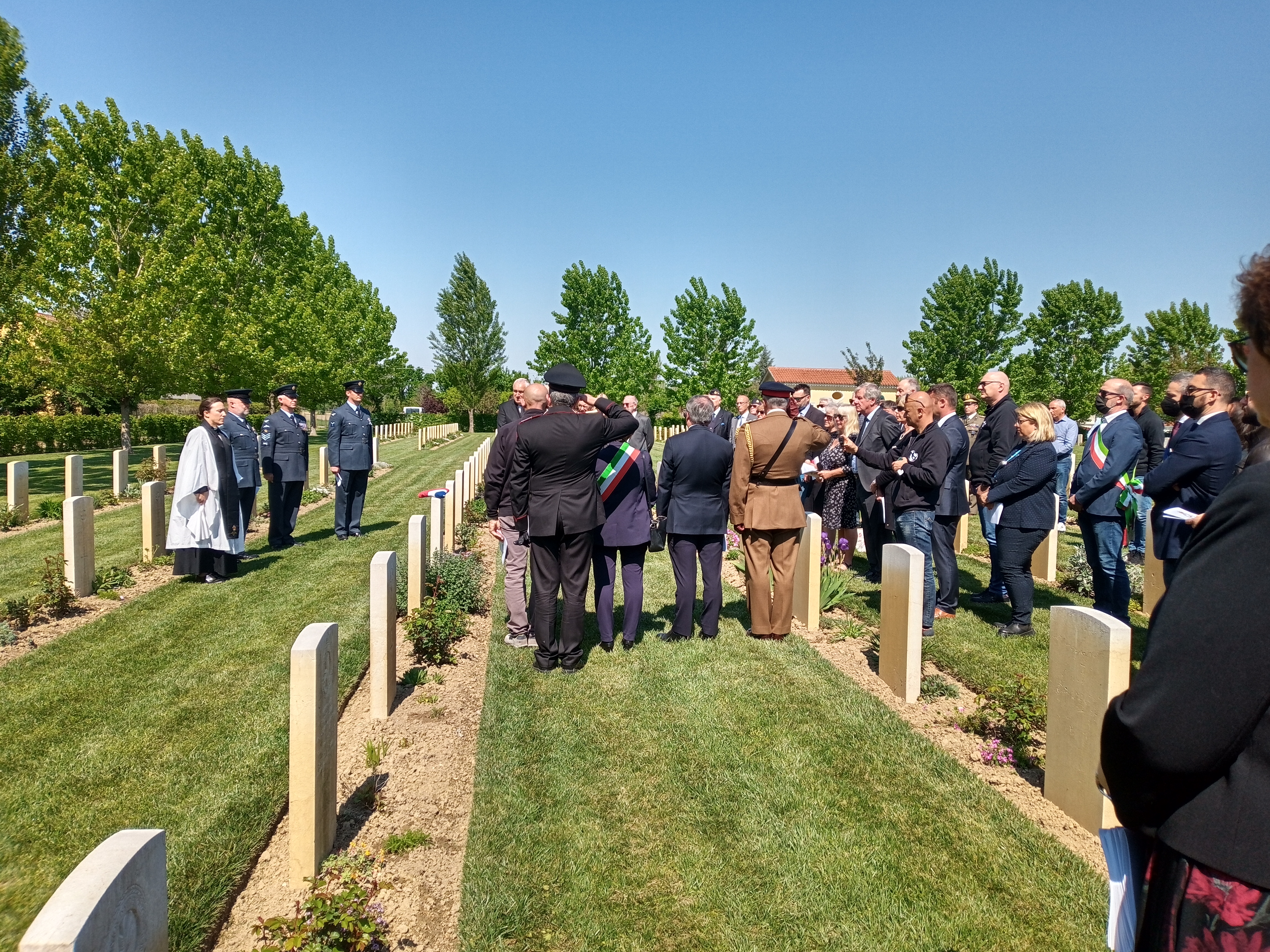 Veterans, personnel and members of the public stand by gravestones.